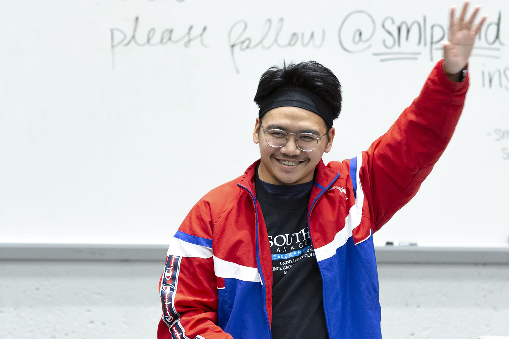 man with hand raised in front of a whiteboard