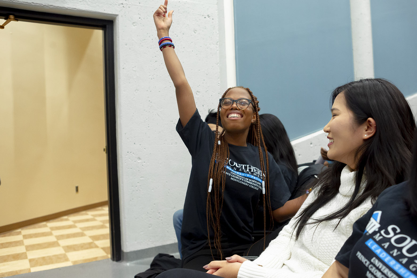 student in front row of auditorium raising hand