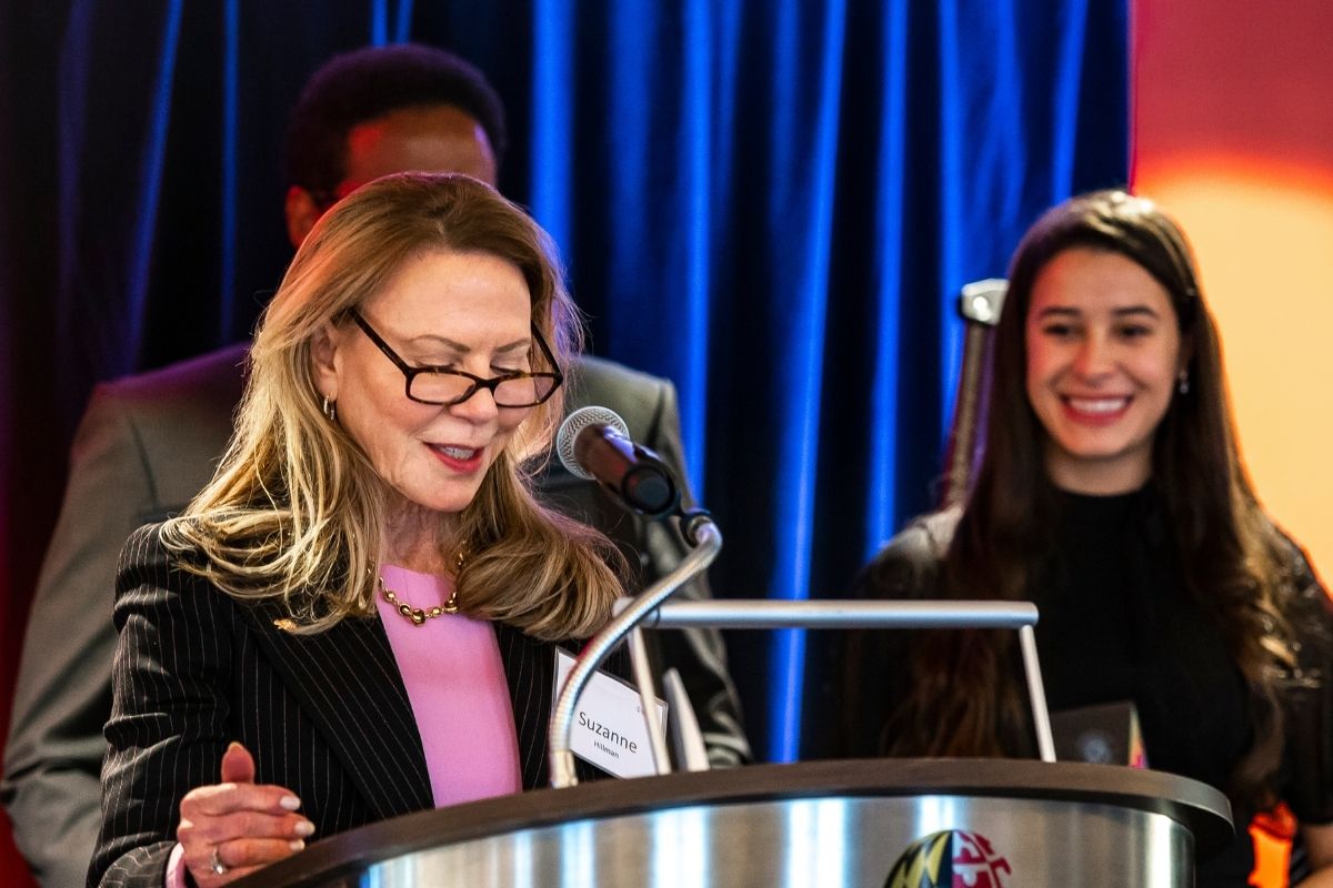 Suzanne at podium with smiling student